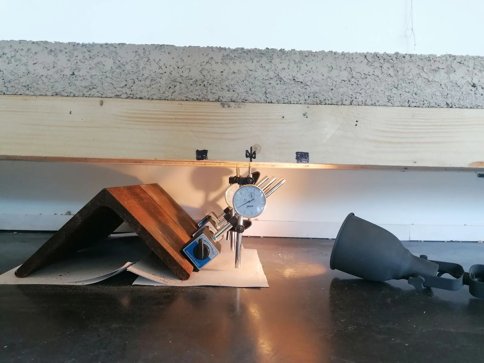 Buigproef op een staal van een hout-kleivloer, met een meetklok die de doorbuiging meet