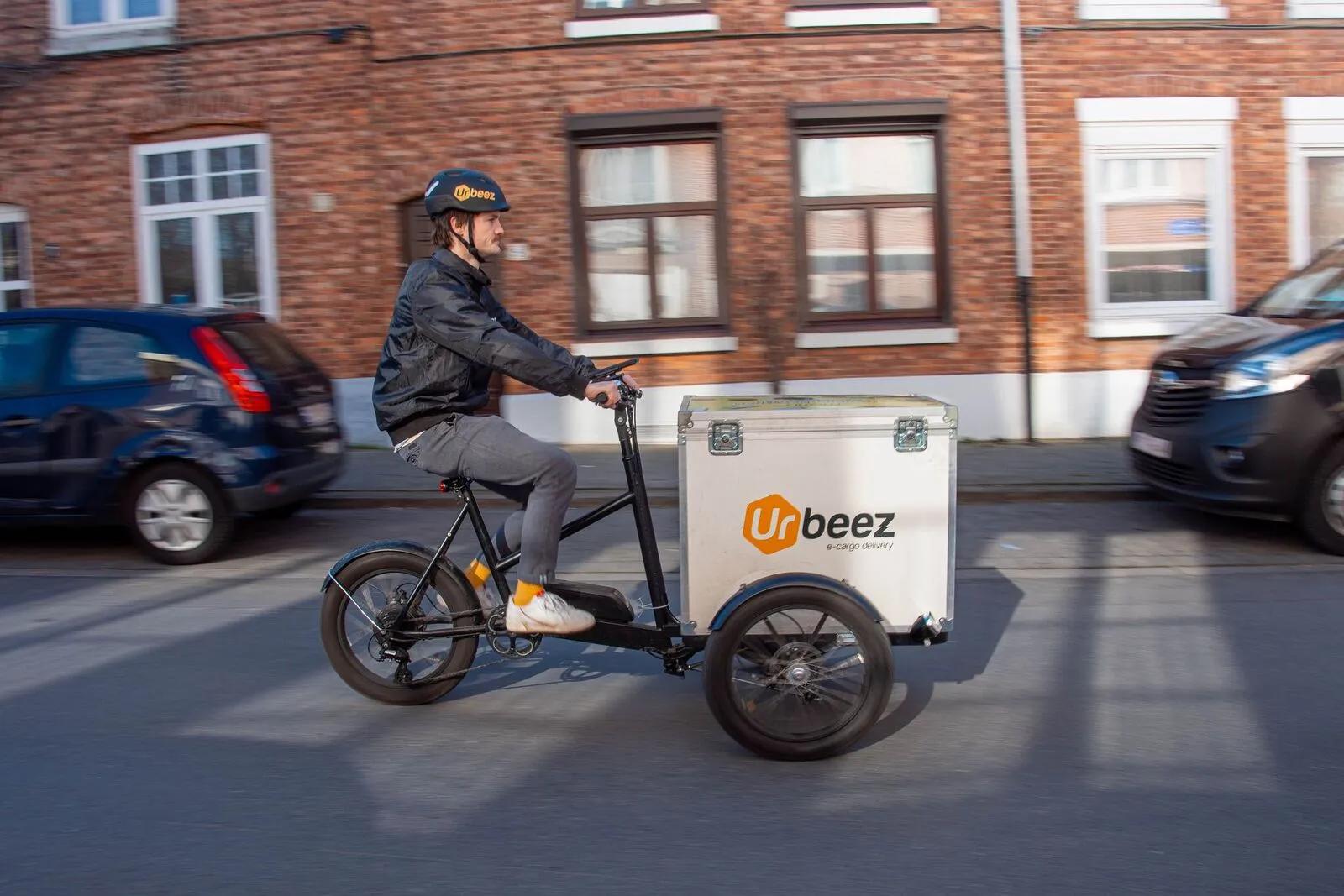 Een koerier van Urbeez levert met een elektrische bakfiets in een stadsstraat