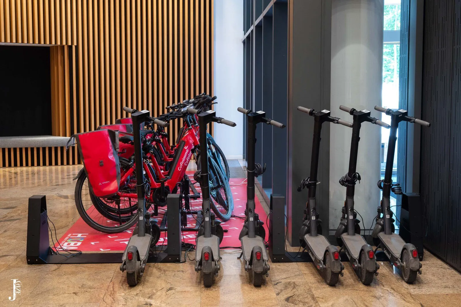 HOOBA-fietsen en -steps in de huisstijl van Cofinimmo in de lobby van een kantoorgebouw