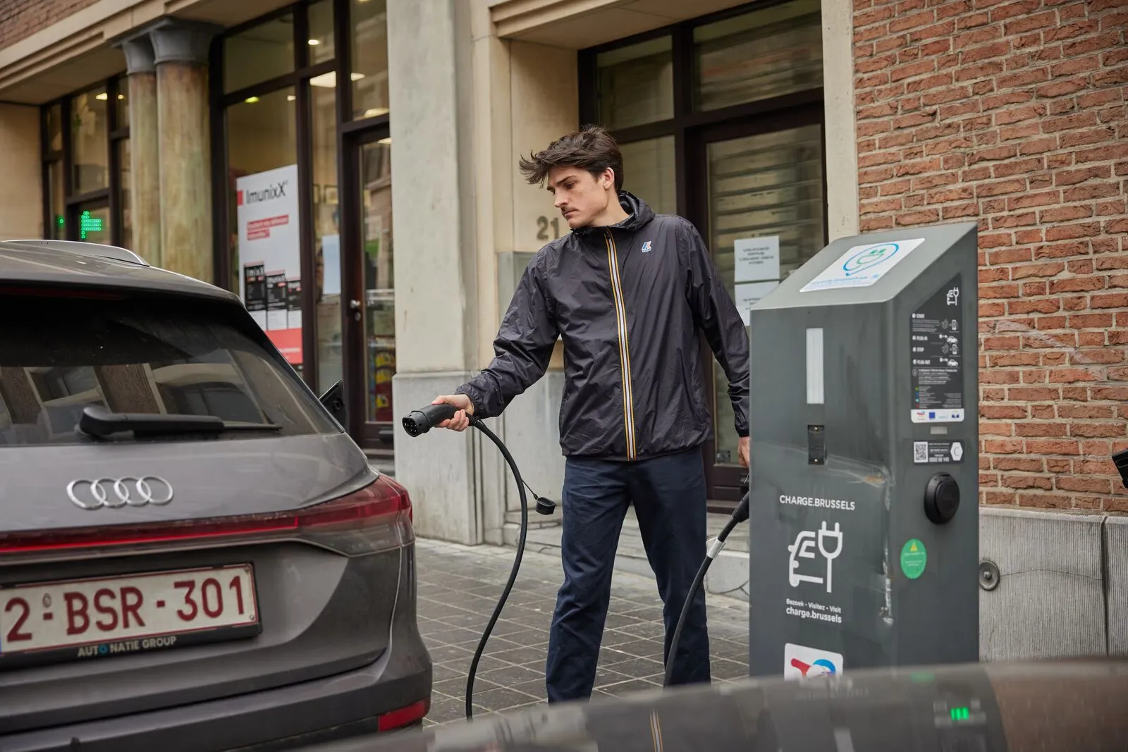 Een medewerker laadt zijn elektrische bedrijfswagen op aan een publieke laadpaal in Brussel