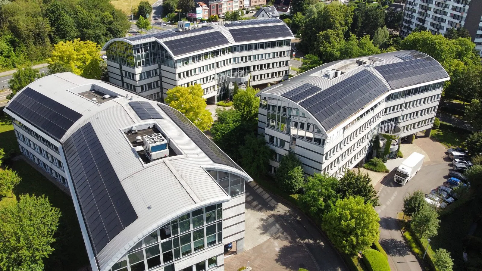 Luchtfoto van de Greenland-kantoorcampus in Jette, met zonnepanelen op de drie gebouwen