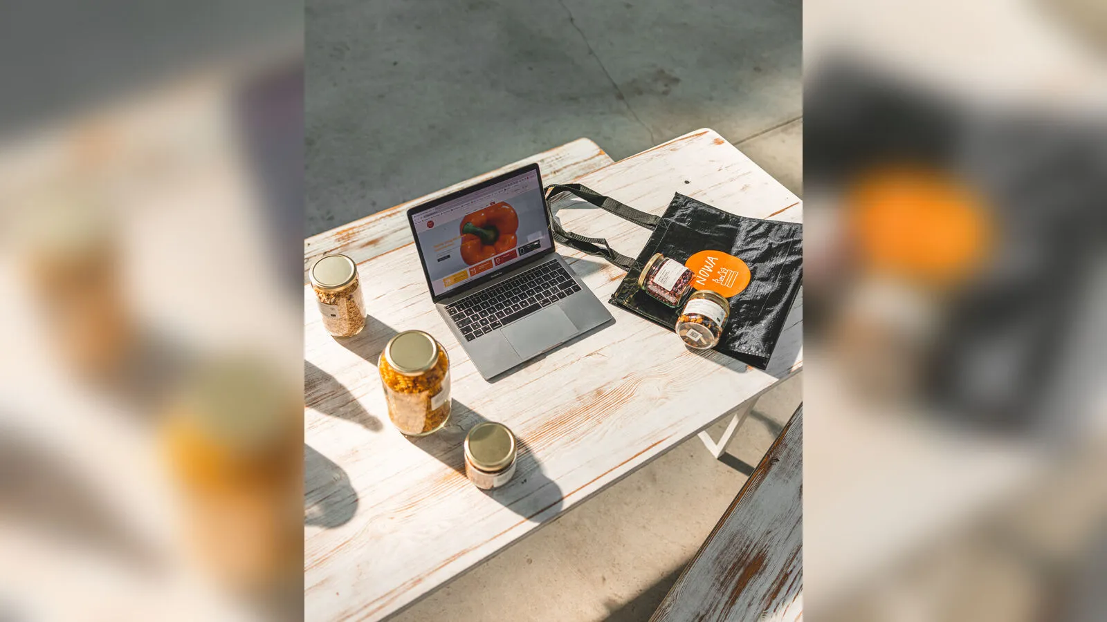 Een bestelling van Nowa Market met bokalen en een herbruikbare tas naast een laptop