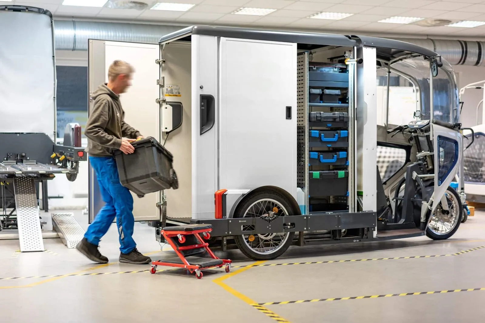 Een ONO-bakfiets wordt geladen in een hub, naast de afneembare container met rekken