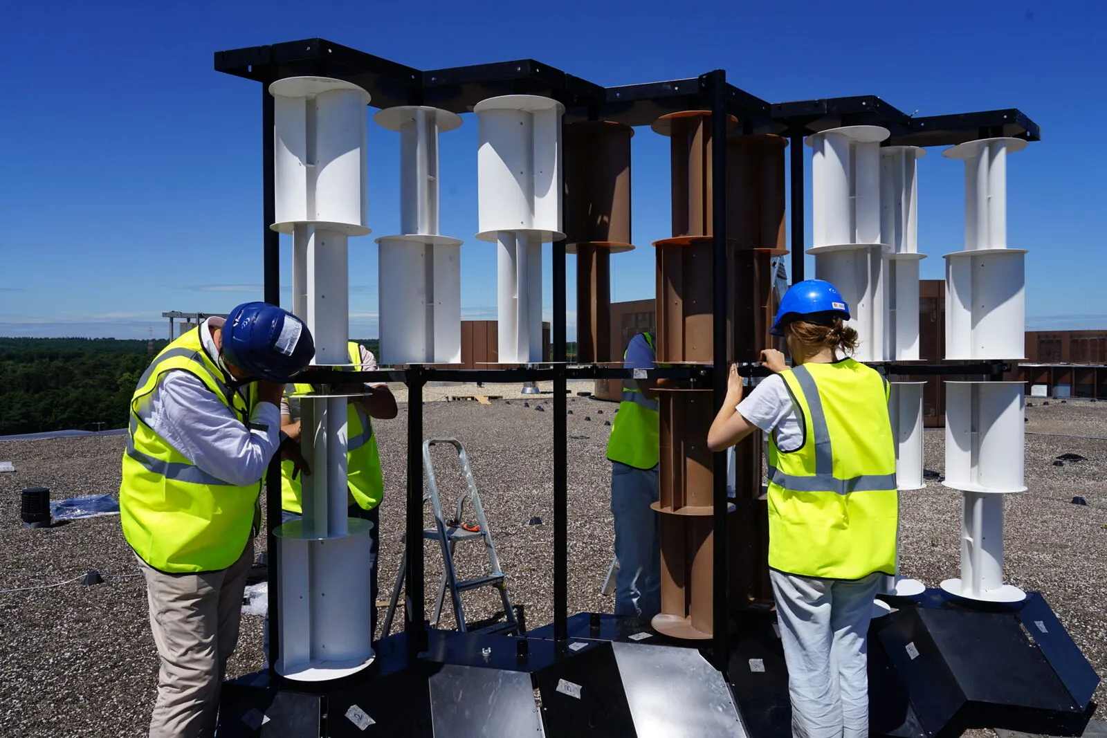 Techniciens en gilets fluorescents assemblant un mur éolien Philéole sur un toit