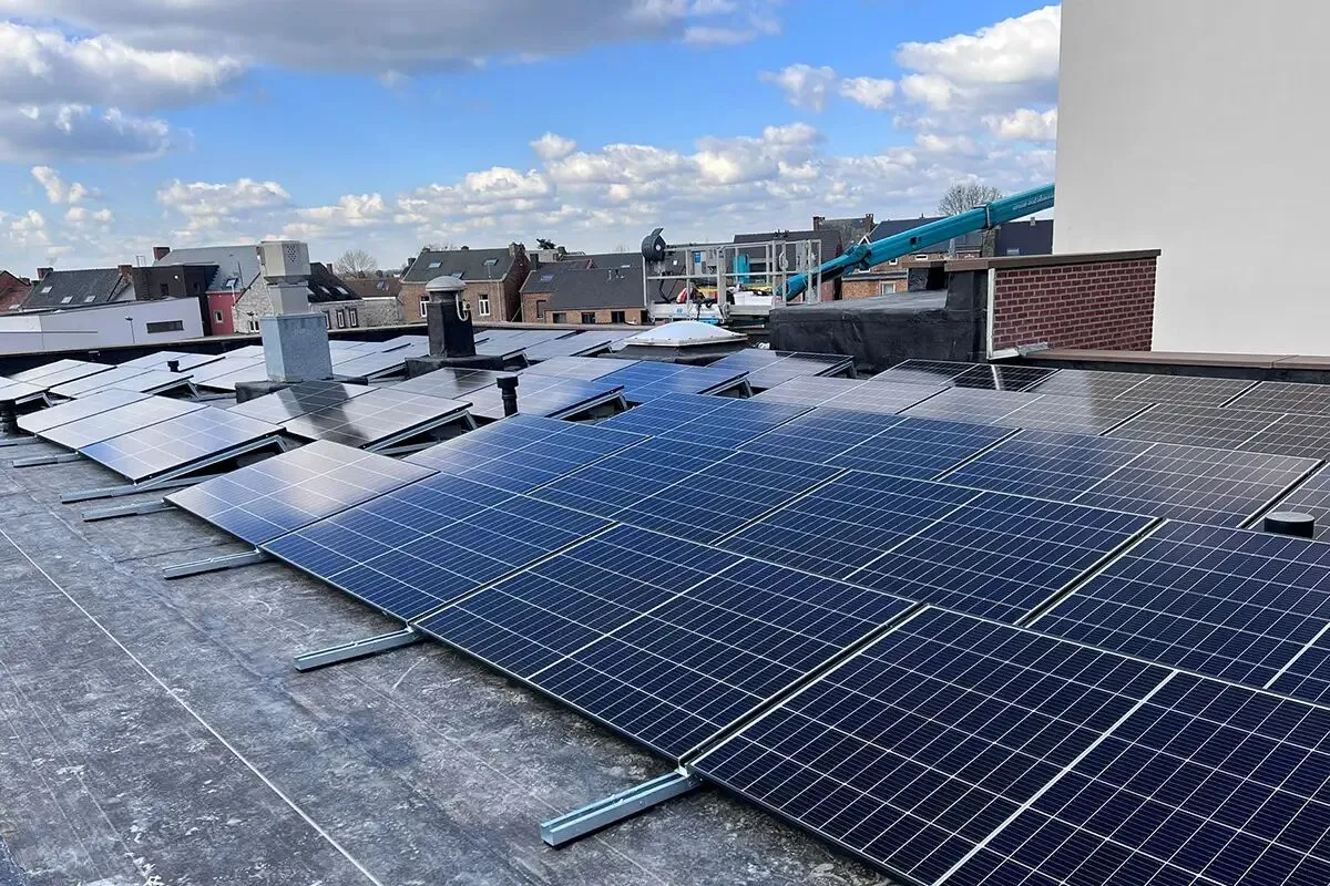 Panneaux solaires posés par Fairwind sur une toiture plate, avec son camion nacelle en arrière-plan