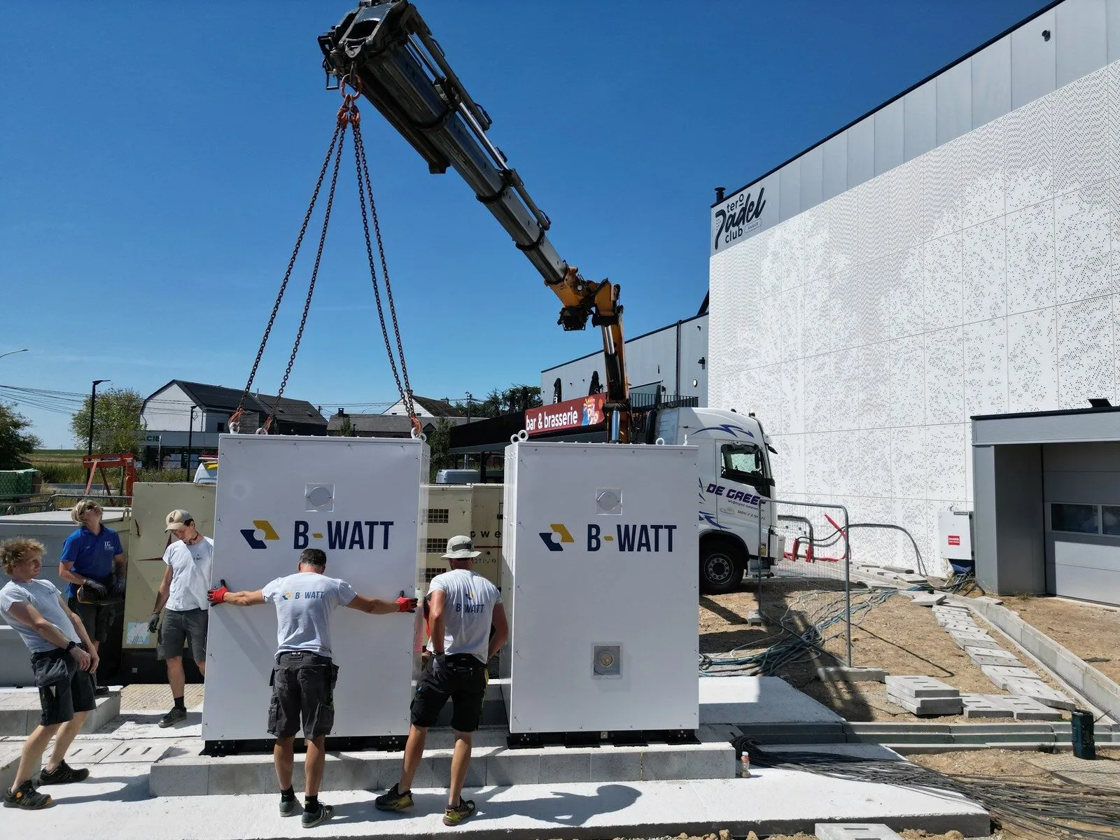 Het B-Watt-team plaatst batterijkasten met een kraan op de site van Tero
