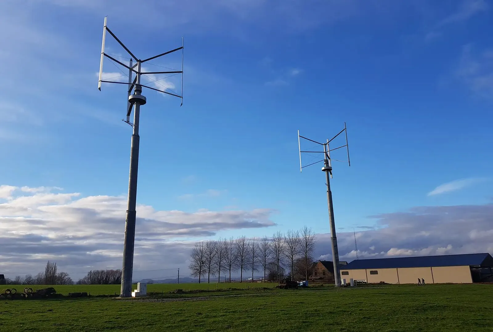 Deux éoliennes à axe vertical Fairwind à côté d'un bâtiment agricole