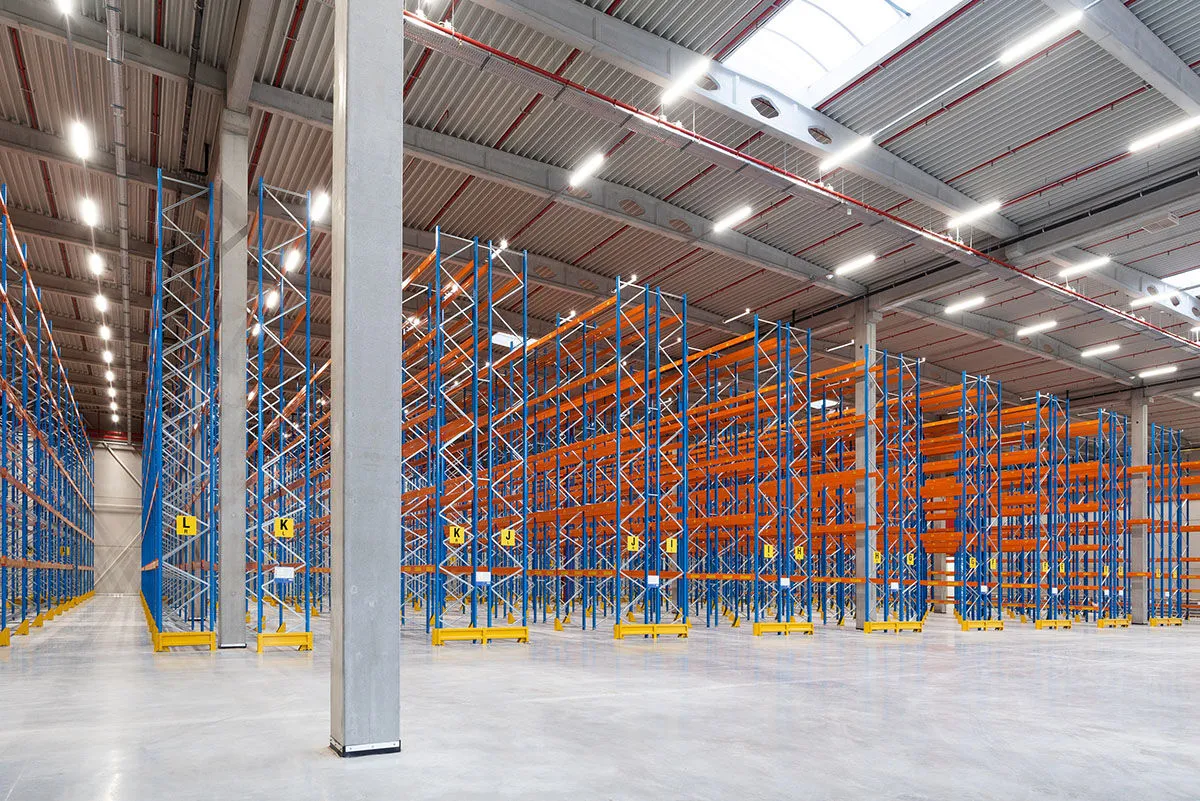 Un grand entrepôt à rayonnages équipé par Brelco d'un éclairage LED en lignes et de chemins de câbles