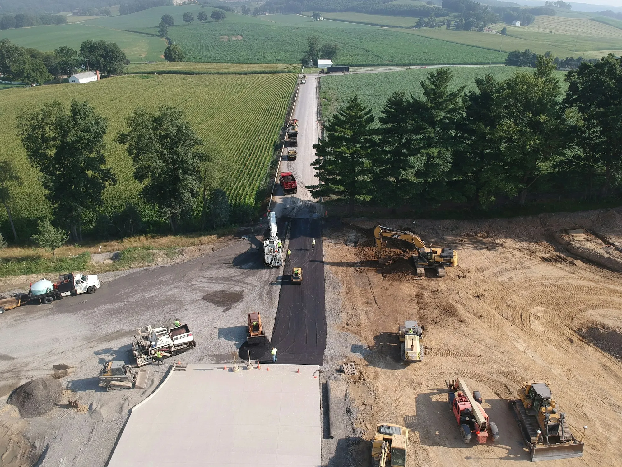 Vue aérienne d'un chantier routier actif avec finisseur et pelle mécanique — projet d'infrastructure publique belge