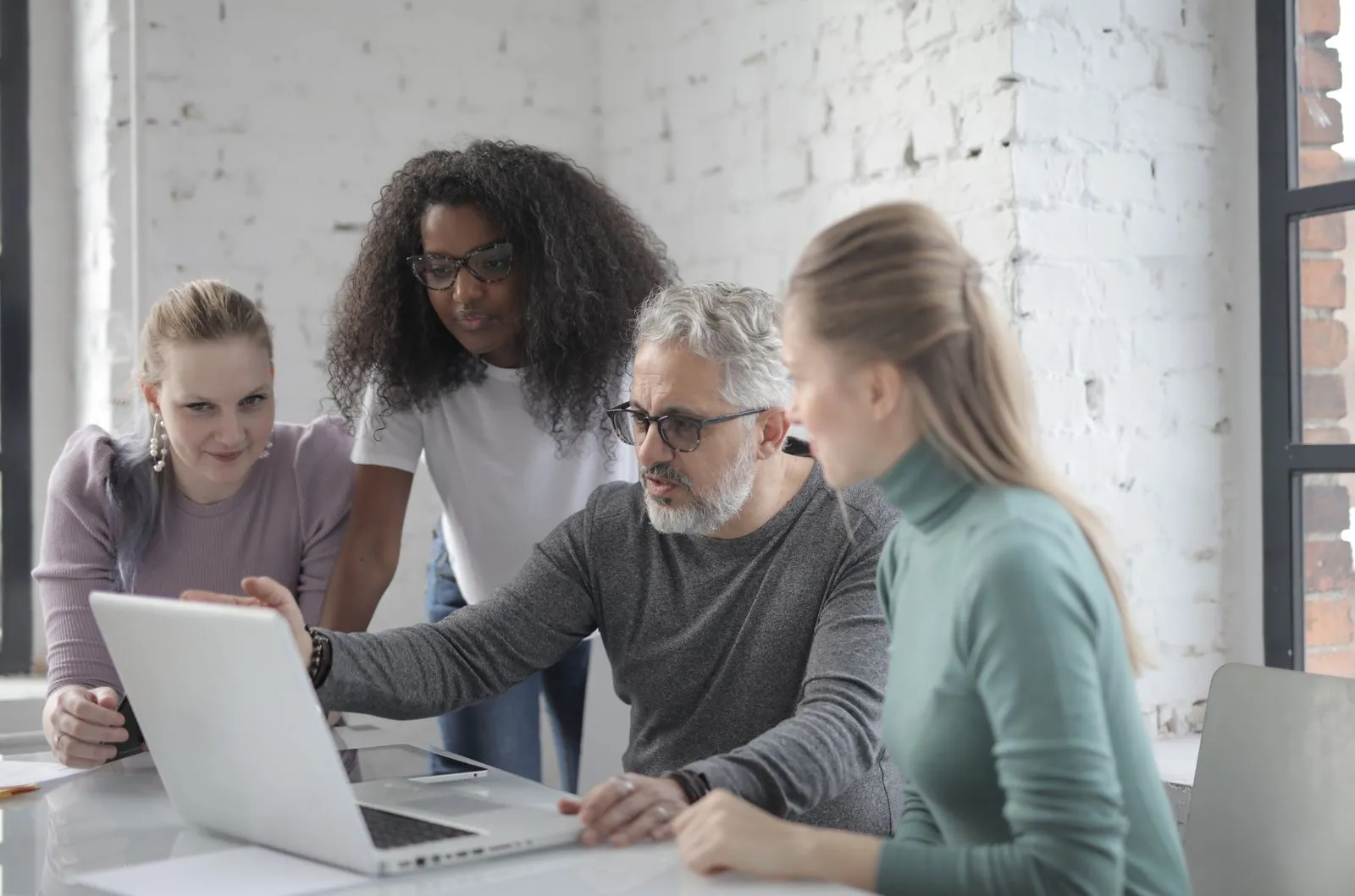 A mentor reviewing a deployment on a laptop with a partner team
